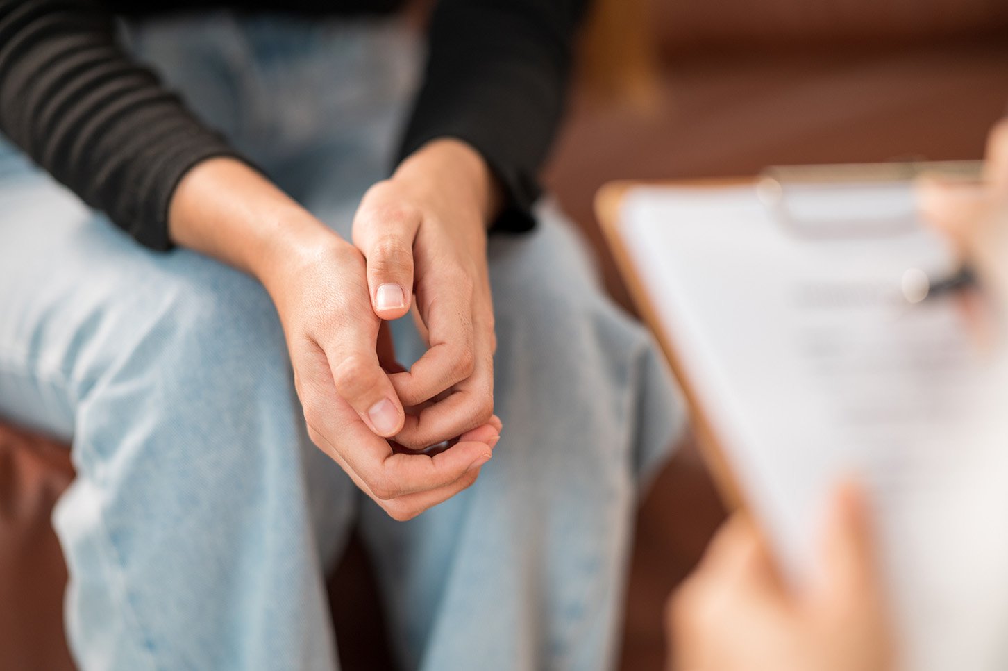 a female patient holds her hand while seeking consultation with a psychologist.